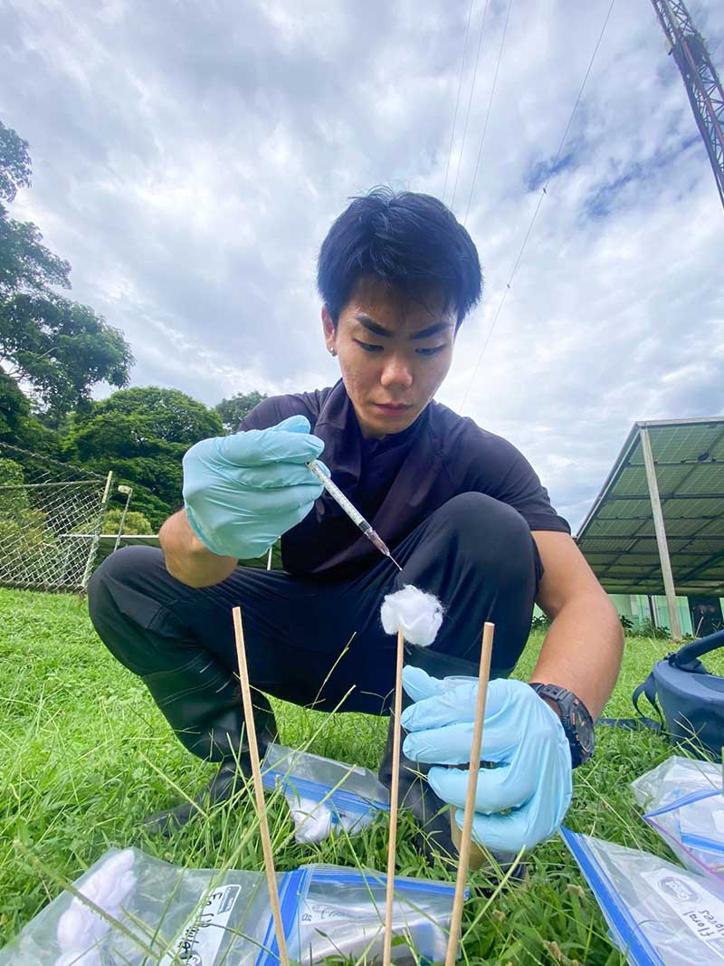A student holding a syringe and conducting a science experiment outdoors