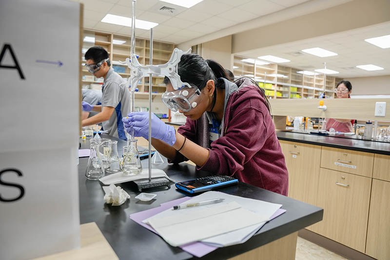 A high school student using a burette in a chemistry lab
