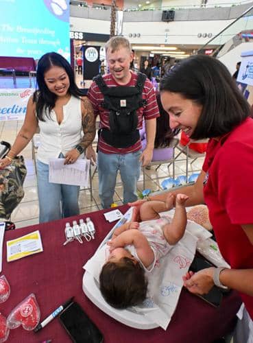 A 5-month-old baby girl getting weighed by a nurse