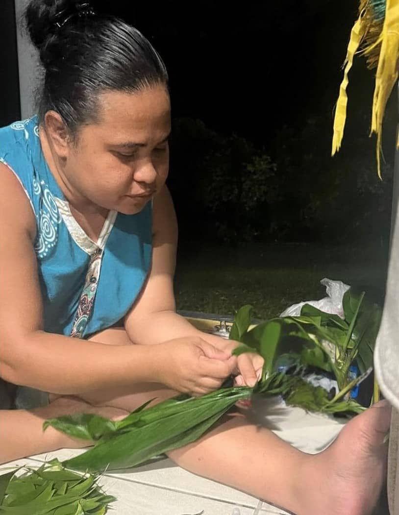 Elizabeth Rutun works on braiding together a lei 