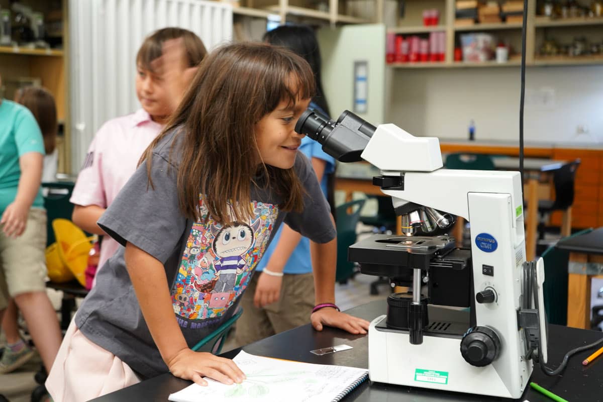 Girl looking inside a microscope