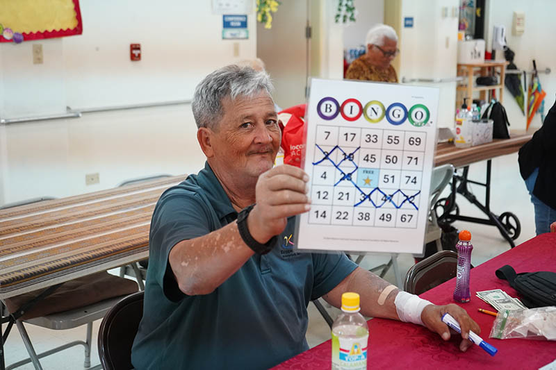 An older man in Guam holding up a Bingo card