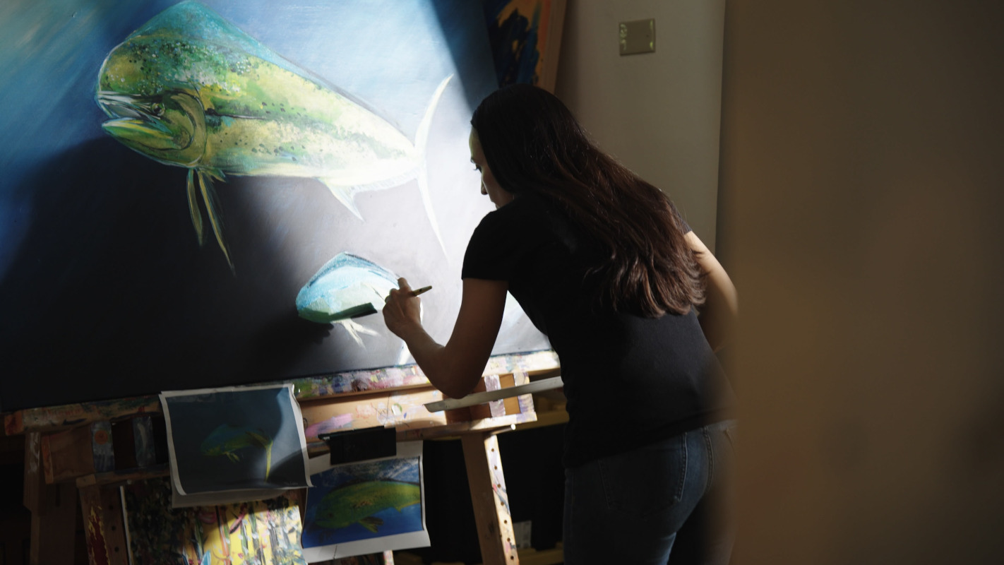Women painting a fish on a canvas