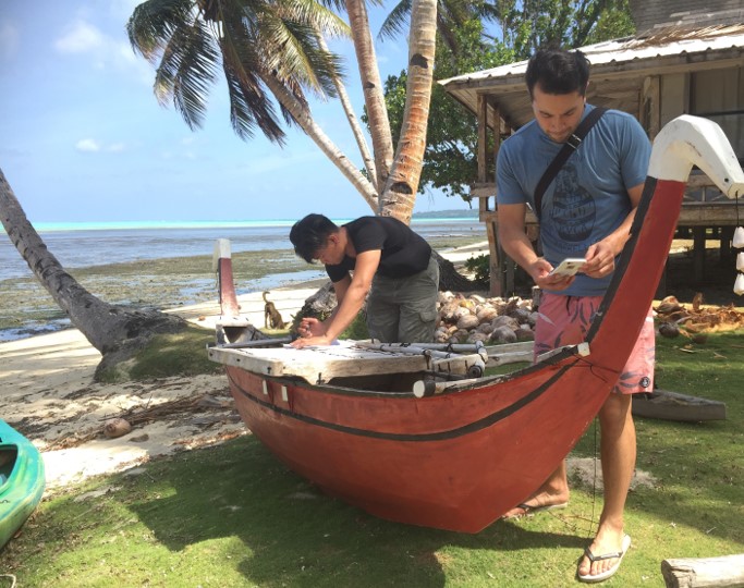 Photo of two people carving a canoe